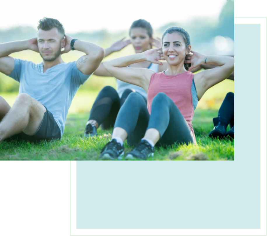 A group of people sitting on the grass doing sit ups.