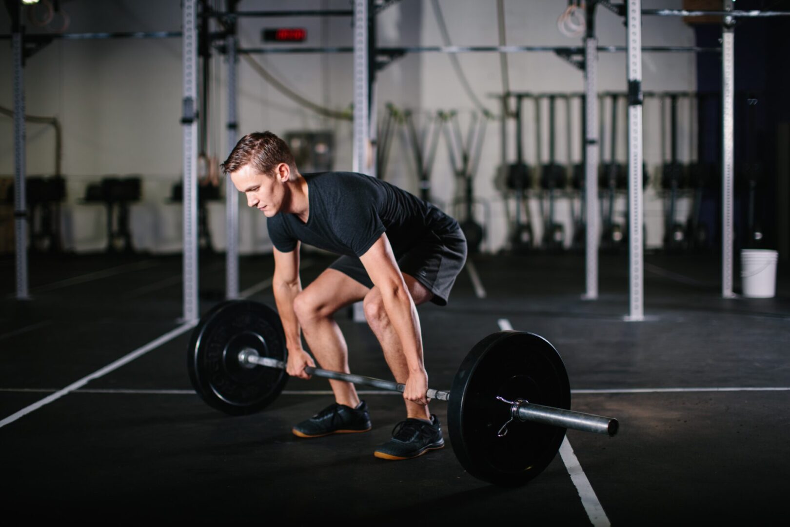 A man is squatting down with a barbell