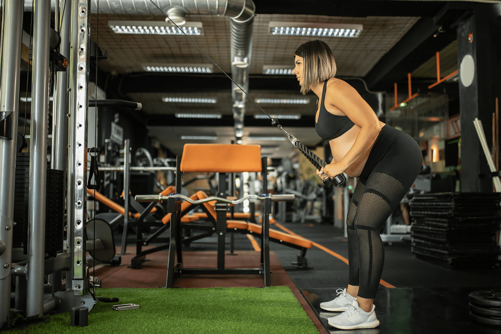 A woman is standing in the gym with a weight.